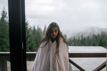 Young woman wrapped in a blanket on the balcony