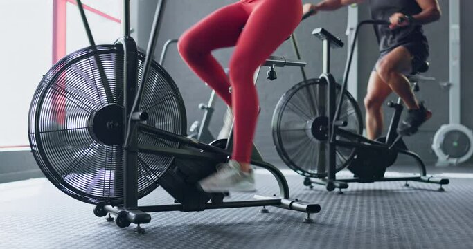 Man, Woman And Air Bike Machine In Gym Workout, Team Training Or Fitness For Cardiology Health, Heart Wellness Or Endurance. Spin Class, Cycling Friends Or Sports People Legs In Body Energy Exercise