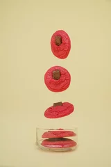 Zelfklevend Fotobehang Pink cookies with chocolate falling in a transparent jar, vertical © Nina Ljusic/Wirestock Creators