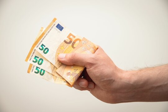 Closeup shot of a young man holding 150 euros in his hand