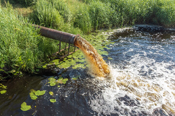 pollution from the pipe enters the river. Dirty water flows into the river.
