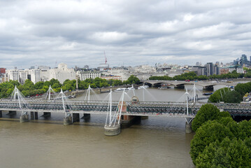 Fototapeta premium Aerial view of Hungerford Railway Bridge and Golden Jubilee Bridges at City of Westminster on a cloudy summer day. Photo taken August 3rd, 2022, London, United Kingdom.