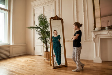 Teen girl looking at mirror and sees middle age woman in reflection of teenage girl in living room...