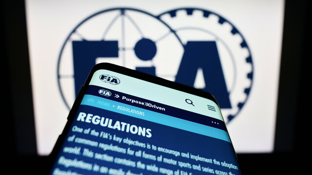 Stuttgart, Germany - 10-24-2022: Mobile phone with website of International Automobile Federation (FIA) on screen in front of logo. Focus on top-left of phone display.
