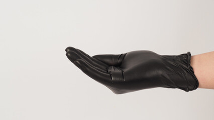 The hand is wearing a black latex glove and do beg hand sign on white background.