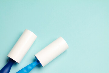 Cloth fabrics cleaner lint roller brush with paper roll blue grip on mint green blue color background. sticky roller, pet cat dog fur dust hair remover. Top view. Flat lay. Copy space. Space for text