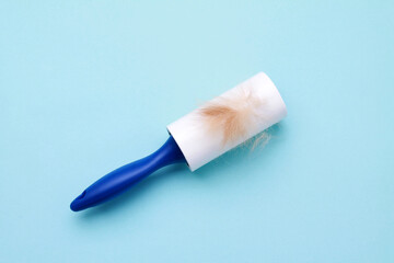 Cloth fabrics cleaner lint roller brush with paper roll blue grip on blue color background. sticky...