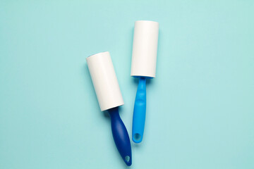 Cloth fabrics cleaner lint roller brush with paper roll blue grip on mint green blue color background. sticky roller, pet cat dog fur dust hair remover. top view