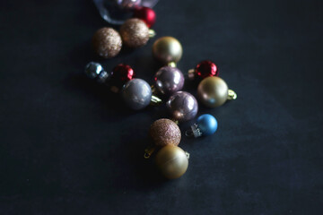 Glass with colorful Christmas baubles on dark background. Selective focus.
