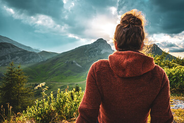 Sporty woman in outdoor jacket watches beautiful mountain scenery at sunset. Falzarego pass,...