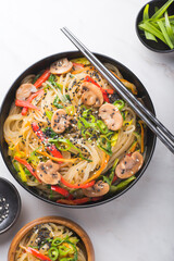  Korean style instant noodle Japchae or Chapchae. Stir-fried Korean vermicelli noodles with vegetables topped with white and black sesame. Korean traditional food style, close-up