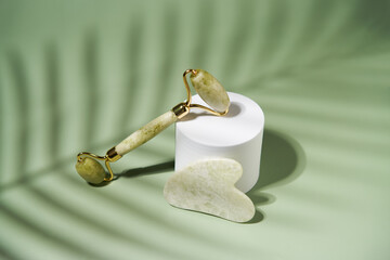 Green jade face roller and Gua Sha scraping for beauty facial massage therapy