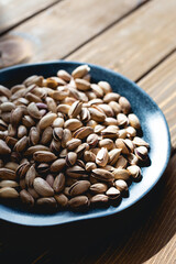 Pistachios on a plate on a wooden table