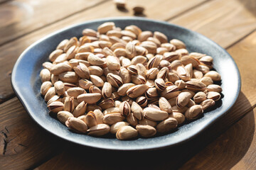 Pistachios on a plate on a wooden table