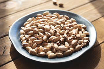 Pistachios on a plate on a wooden table