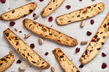 Biscotti cookies food background with cranberry and pistachio nuts, top view. Biscotti or cantucci are traditional italian baked sweet biscuits, popular during winter holidays as a snack or dessert - obrazy, fototapety, plakaty