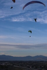 Vertical shot of people paragliding on the mountainous background under the cloudy sky