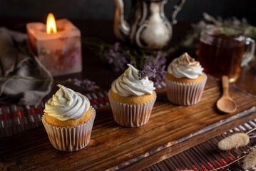 muffins or madeleines on a can and a wooden board with meringue and cream on top with an old teapot cup of tea and decorated with natural flowers