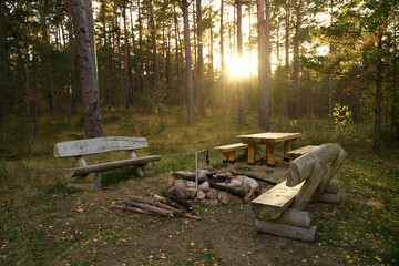 A place to rest on a tourist forest trail. Recreation area in the forest for tourists with a wooden table, benches and a stone fireplace.