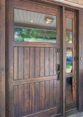Vertical Dark wood front door with glass panel and sidelight near the picture window