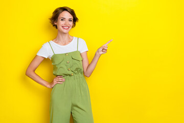Photo of adorable gorgeous girl with bob hairdo wear white t-shirt indicating empty space arm waist isolated on yellow color background
