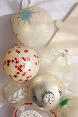 White and transparent Christmas tree ornaments, illuminated by sunlight. Flat lay.