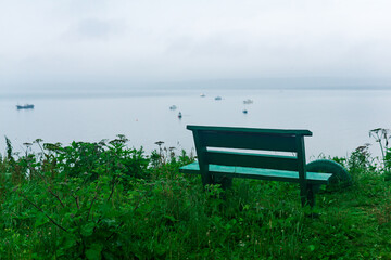 lonely bench among the burdocks on a high seashore at dusk