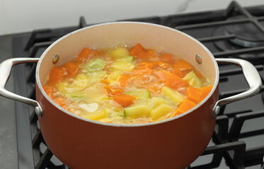 closeup of boiling pot of vegetable soup on stove top. Vegetarian and diet food. selective focus
