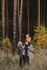 Fototapeta premium Happy caucasian couple with little baby boy. Parents and son having fun together among autumn leaves. Mother and father playing with toddler outdoors. Family, parenthood, childhood, happiness concept.