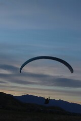 Vertical shot of a person paragliding in between beautiful mountains