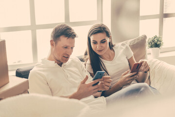 Obraz premium happy young couple looking at their smartphone screen .