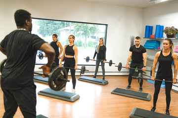 group people lifting weight over their heads looking focused, working out in a gym with other people