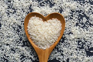 Long grain rice in heart shaped spoon. Flat lay