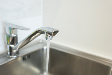 Close up water tap, flow water in bathroom with sink. Modern clean hause. Hygiene concept.
