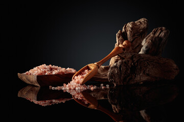 Pink salt with an old snag on a black reflective background.