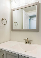 Vertical Single vanity sink in a small white bathroom with towel ring holder
