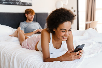 Young beautiful african woman lying with her working boyfriend