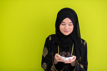 modern muslim woman holding a plate full of sweet dates on iftar time in ramadan kareem islamic...