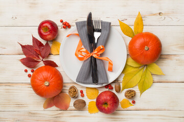 Plate with cutlery, napkin and autumn decor on wooden background, top view. Thanksgiving table setting