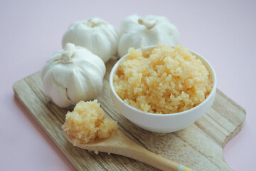 close up of minced garlic on a wooden spoon 