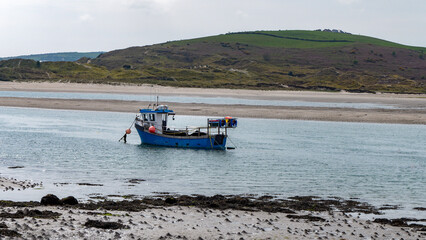 Obraz premium A small fishing boat moored near the shore at low tide. Seaside landscape.