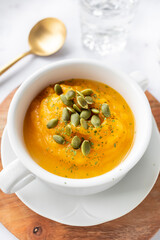Homemade pumpkin cream in a white bowl. Vegetarian and vegan food ready to eat. Delicious vegetable cream