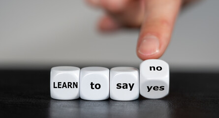 Hand turns dice and changes the expression 'learn to say yes' to 'learn to say no'.