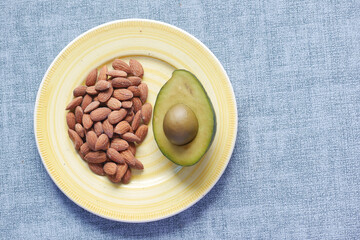 close up of slice of avocado and almond nut on chopping board.
