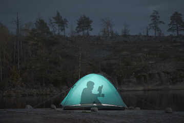 A man spends leisure time in a tent reading a book. Take a break from the crazy world