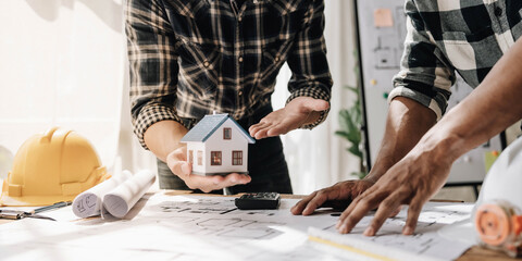 Concept architects, engineer holding pen pointing equipment architects On the desk with a blueprint in the office, Vintage, Sunset light.Selective Focus