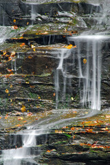 New England waterfall. Cascading water over rocks in the forest. Small trickling waterfall in the woods with fallen leaves