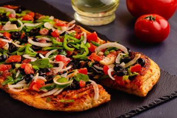 Homemade vegan pizza with tomatoes, peppers, olives, onions.