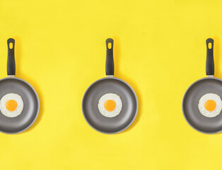 Frying pan with fried egg on the yellow background. Pattern. Flat lay. Top view.