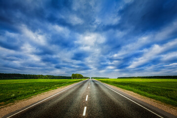 Travel concept background - road under dramatic stormy cloudy sky